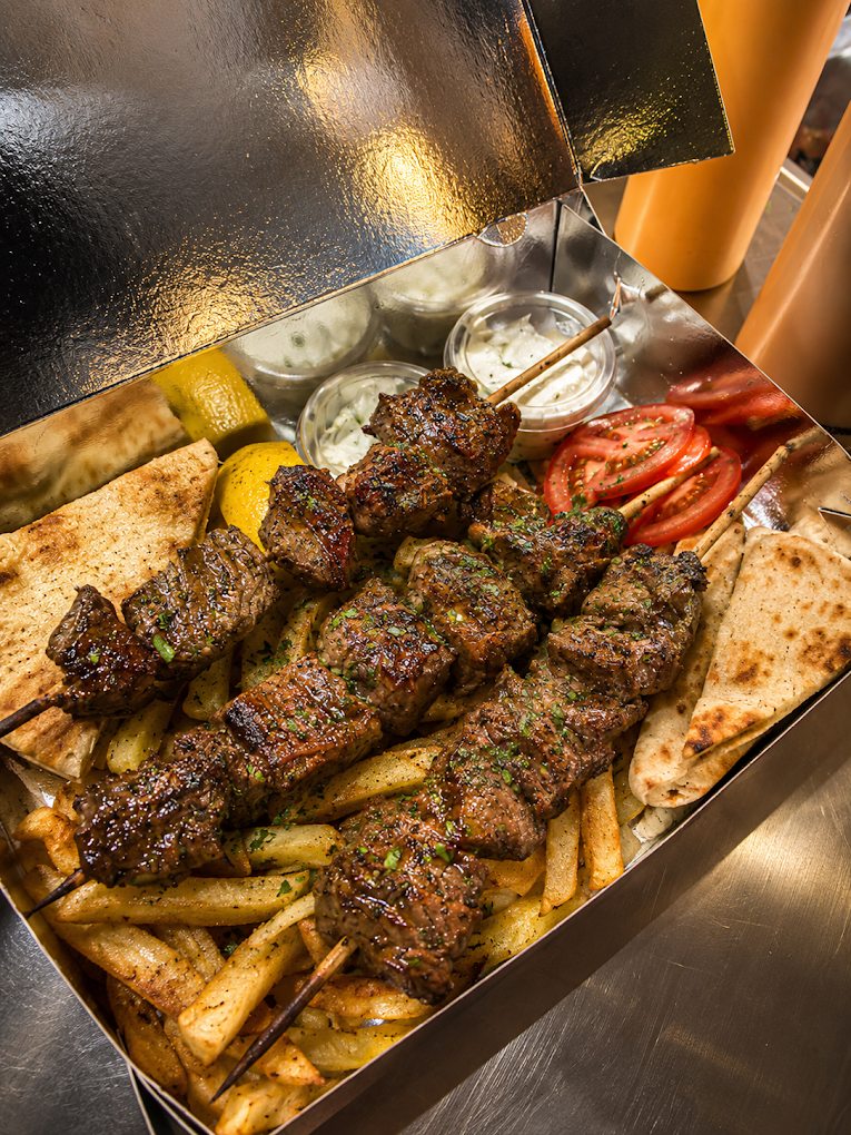 Beef souvlaki platter with fries, pita, tomato, lemon and sauces