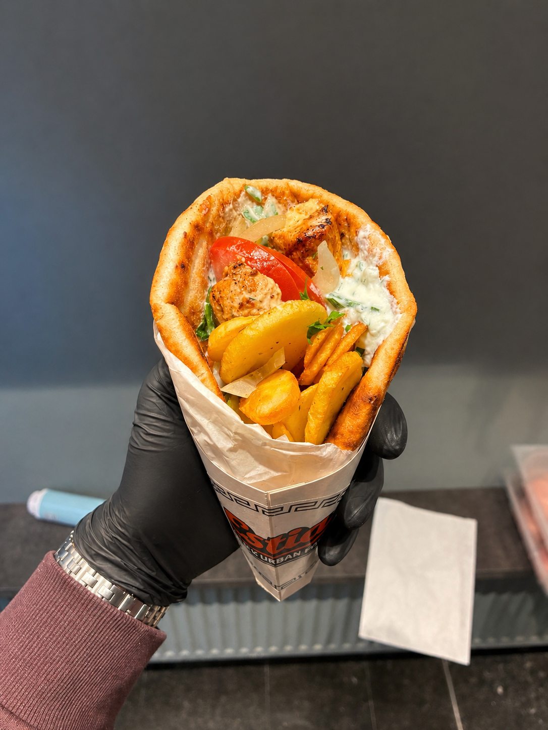 Chicken souvlaki wrap with fries, tomato, onion and tzatziki in ESTIA paper