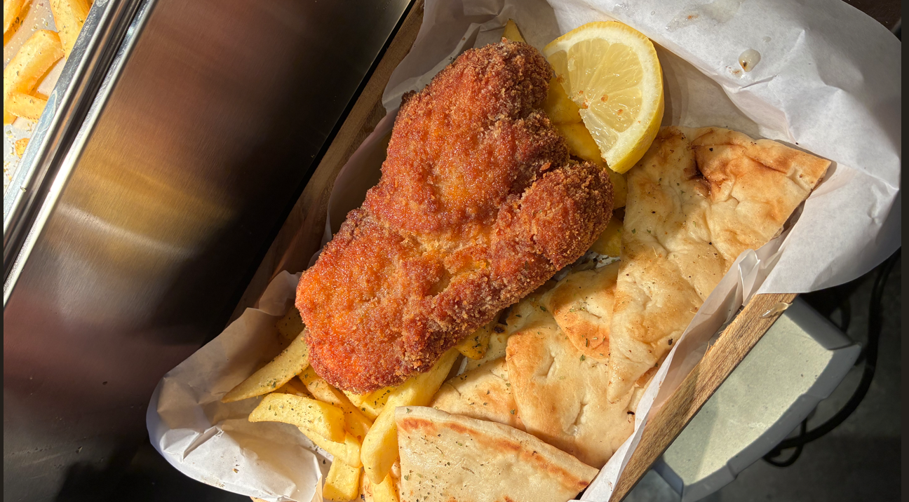 Freshly prepared ESTIA meal with crispy chicken, fries, pita and lemon