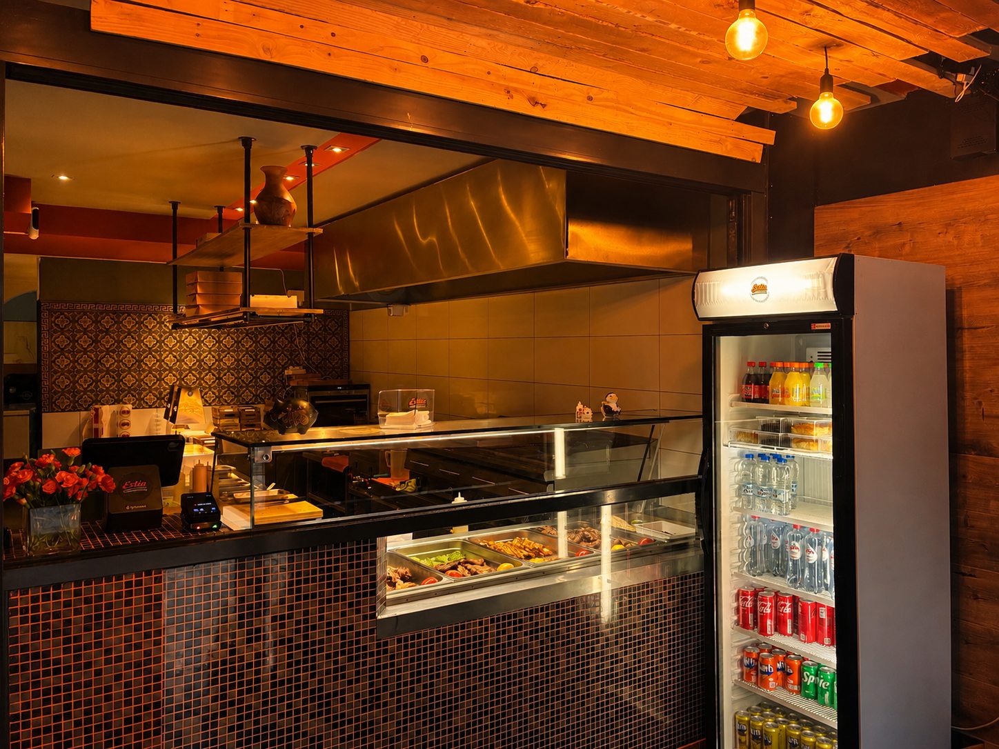 Warm ESTIA interior with wooden ceiling, orange tiles, display counter and drinks fridge